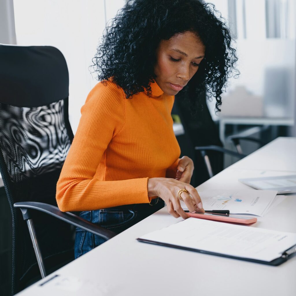 Diligent Black female accountant in her 30s, managing ledgers in a modern