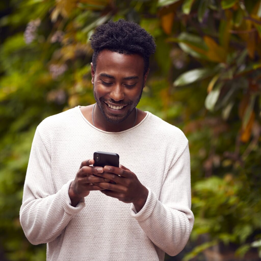 Male Vlogger Or Social Influencer In City Using Mobile Phone On Street To Post To Social Media