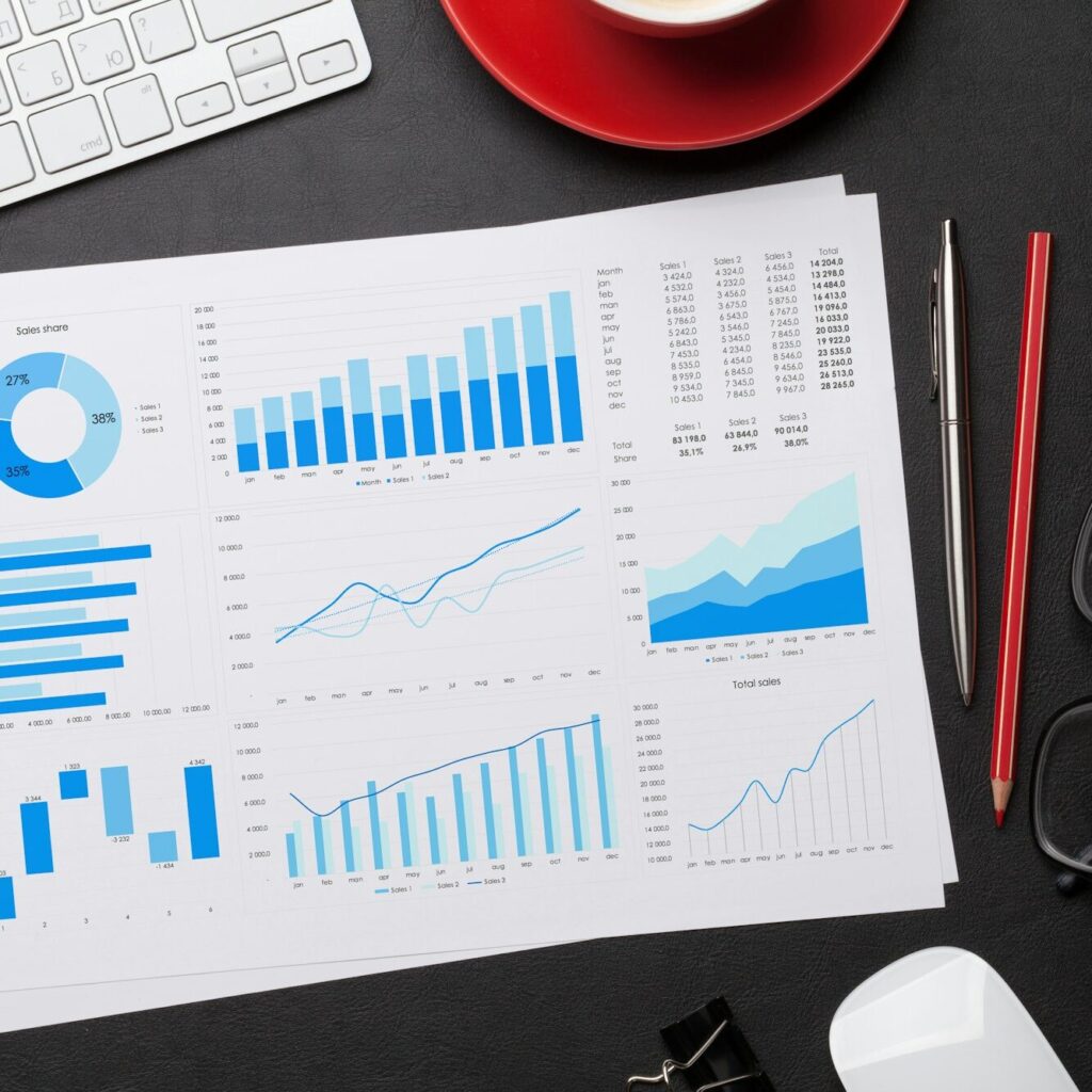 Financial report with graphs, pens, laptop keyboard, and coffee cup on desk – Zidika Consulting Kenya