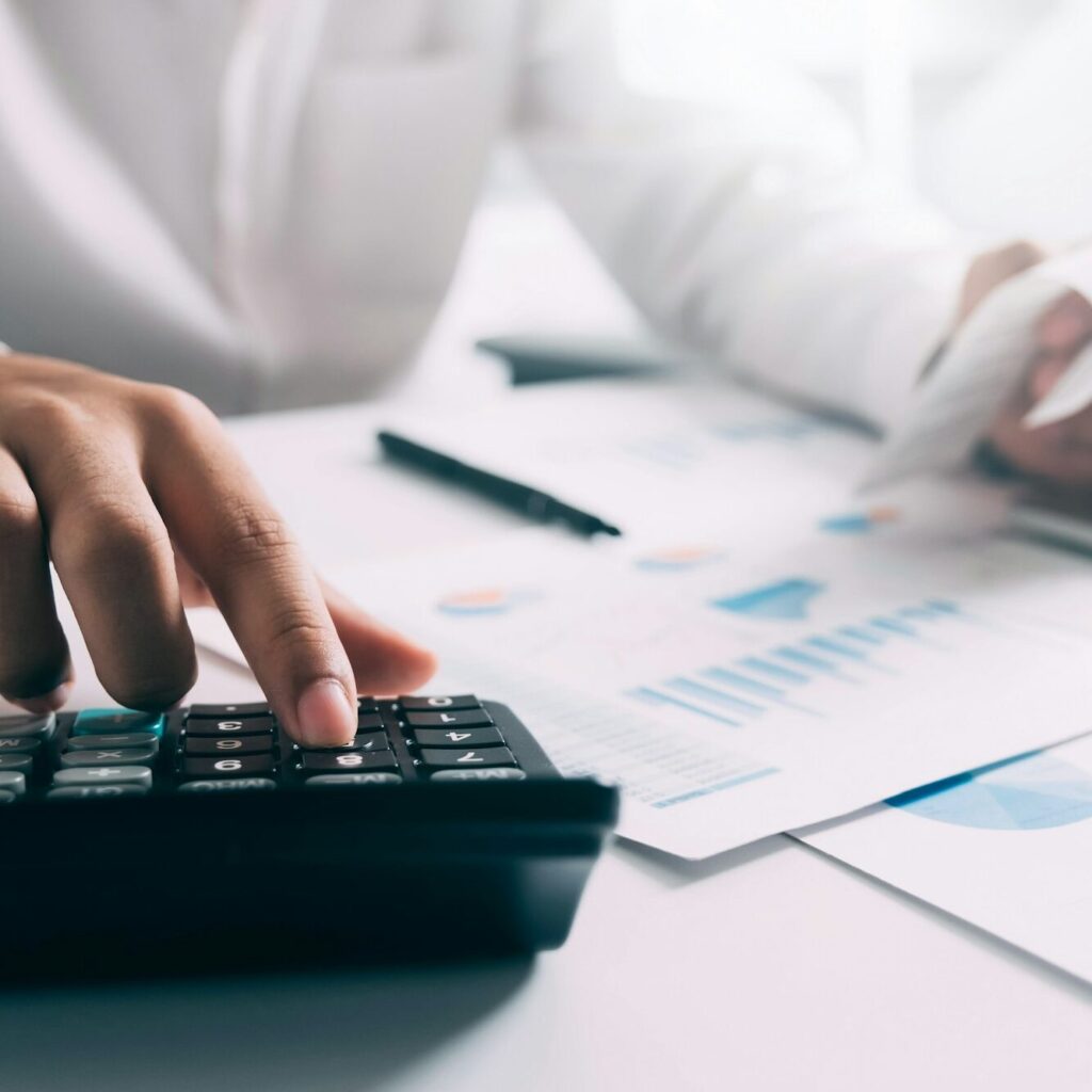 Businessperson punching figures into a calculator beside financial reports – Zidika Consulting, Kenya