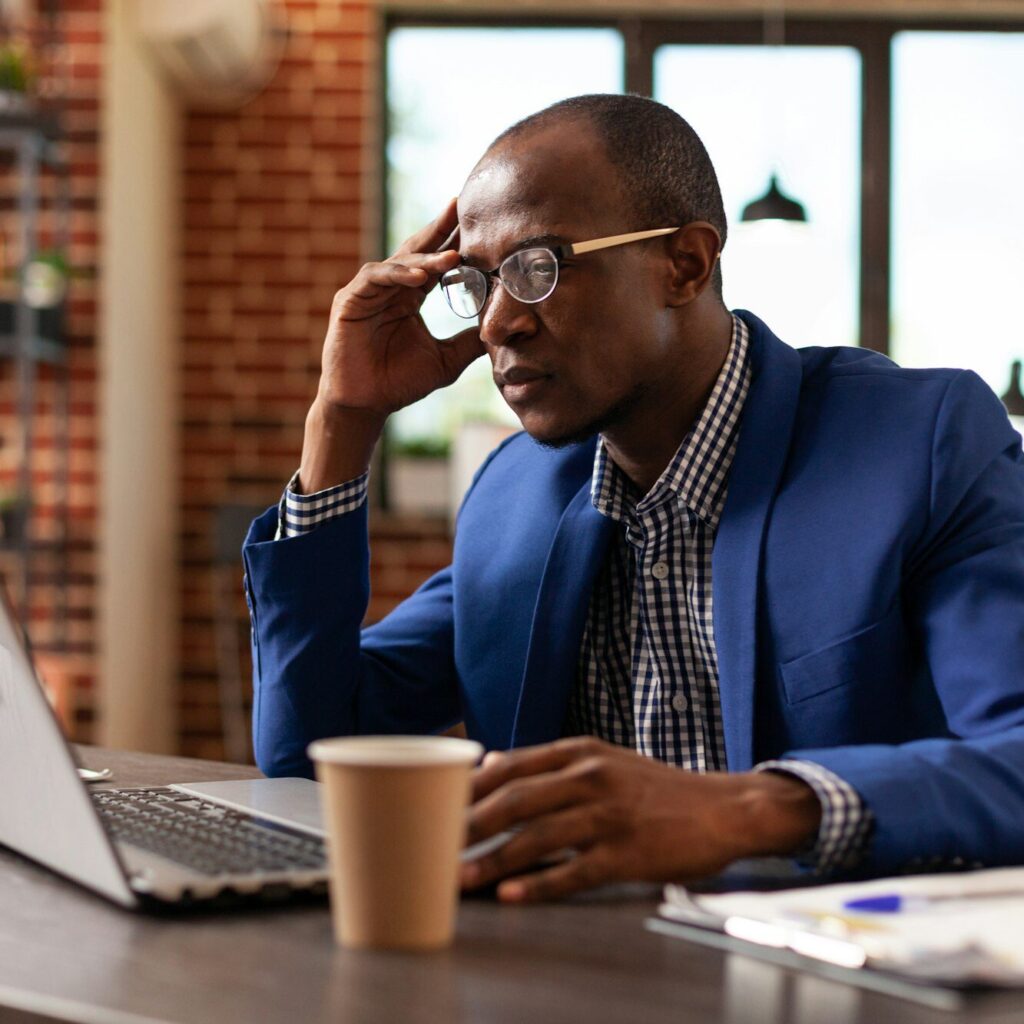 Business professional focused on laptop with coffee – financial thinking by Zidika
