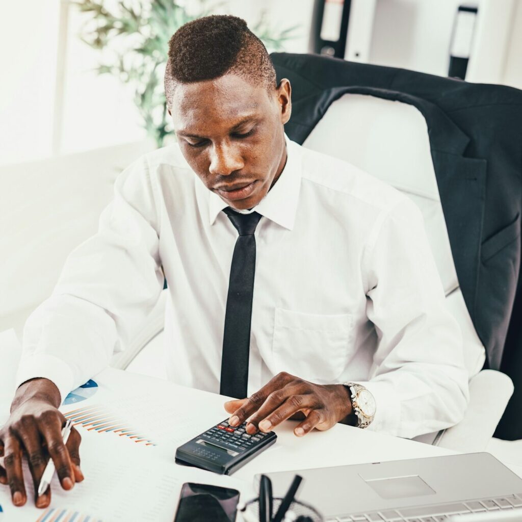 Accountant in Nairobi working through outsourced records on a calculator – Zidika Consulting