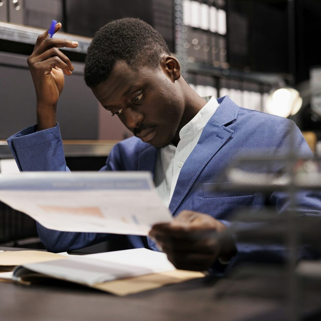 Man in Nairobi scratching his head while reviewing bookkeeping records – Zidika Consulting